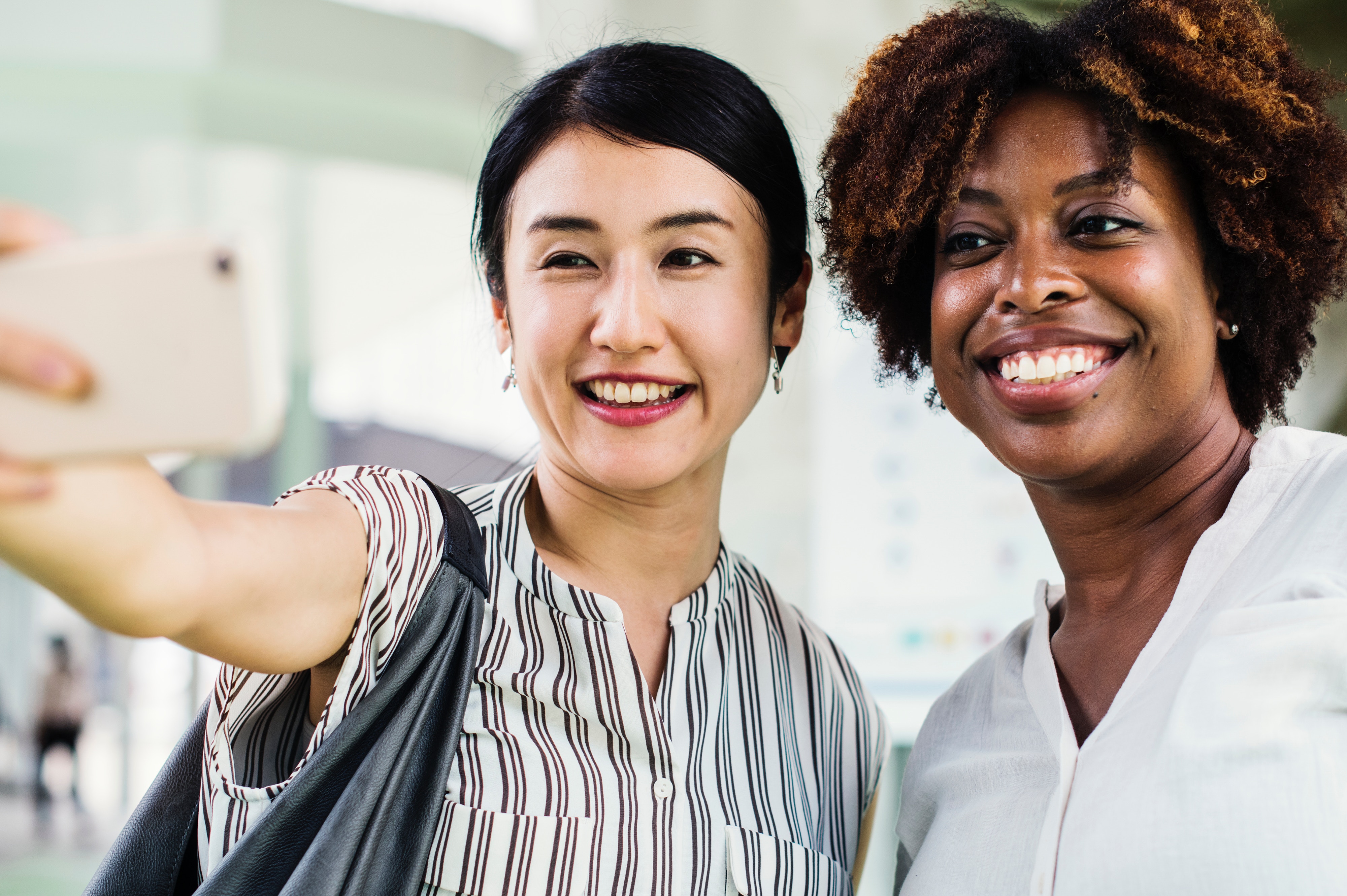 A woman taking picture of herself and a happy friend.