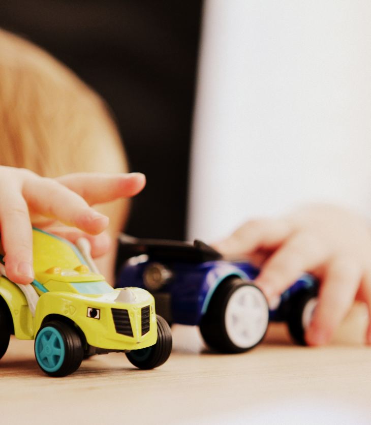 toddler playing with two cars